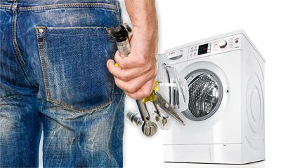 Person in Jeans mit Werkzeug in der Hand steht vor einer Waschmaschine. Person in Jeans mit Werkzeug in der Hand steht vor einer Waschmaschine.